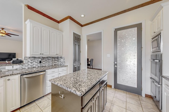 kitchen with tasteful backsplash, white cabinets, a center island, stainless steel appliances, and light stone countertops