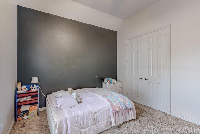 carpeted bedroom with lofted ceiling and a closet