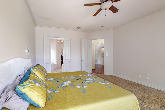 carpeted bedroom featuring ceiling fan, ensuite bath, and ornamental molding