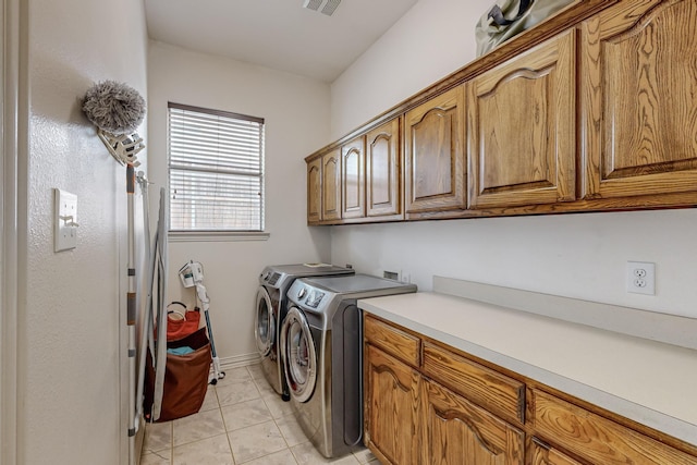 clothes washing area featuring cabinets, light tile patterned floors, and washing machine and clothes dryer