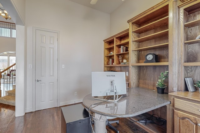 home office with dark wood-type flooring and a chandelier