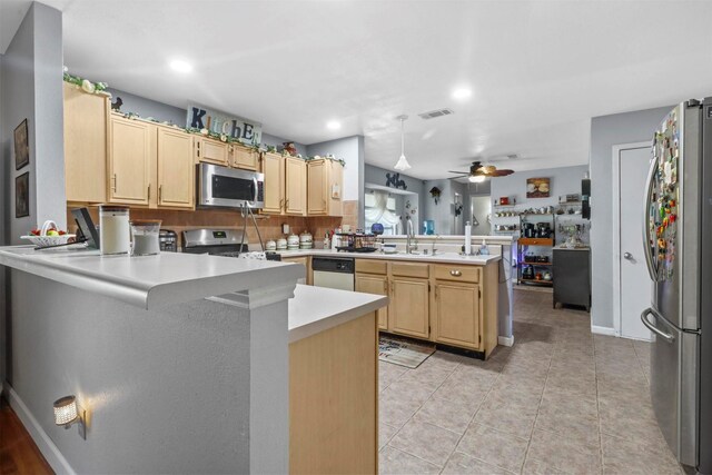 kitchen featuring light tile patterned flooring, ceiling fan, stainless steel appliances, light brown cabinets, and kitchen peninsula