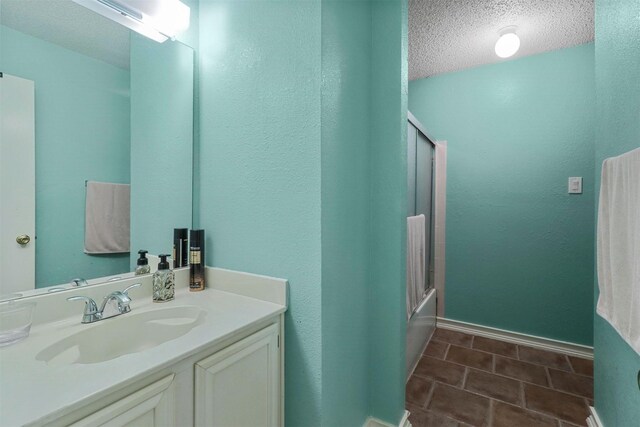 bathroom with shower / bath combination with glass door, vanity, a textured ceiling, and tile patterned flooring