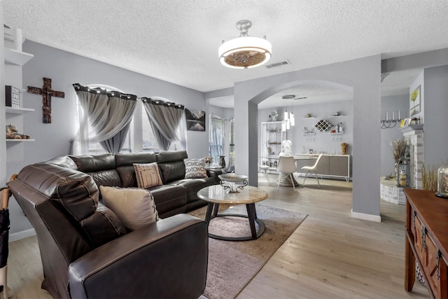 living room featuring light wood-type flooring and a textured ceiling