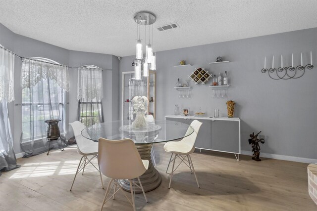 dining space with light hardwood / wood-style floors and a textured ceiling