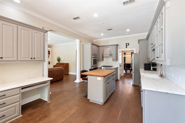 kitchen featuring appliances with stainless steel finishes, decorative columns, gray cabinetry, and dark hardwood / wood-style floors