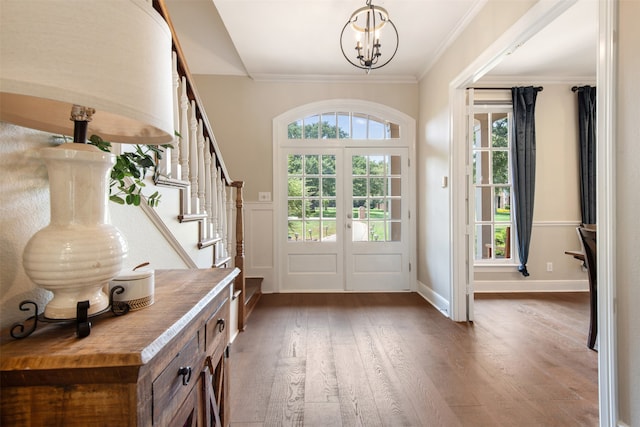 entryway with crown molding, dark wood-type flooring, a wealth of natural light, and french doors