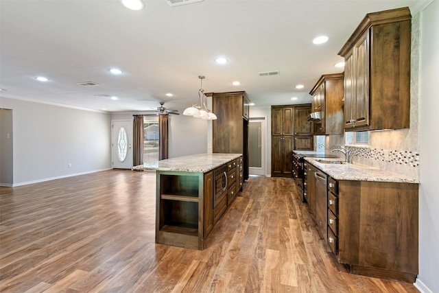 kitchen with light stone counters, dark hardwood / wood-style flooring, a kitchen island, and decorative light fixtures