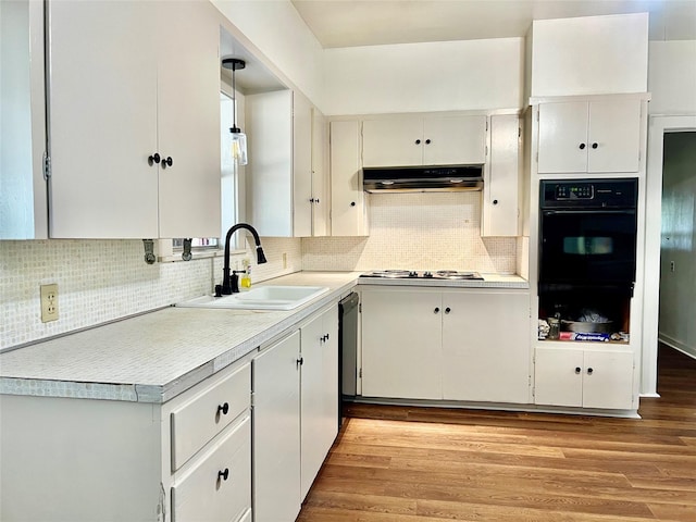 kitchen featuring black oven, white cabinetry, sink, hanging light fixtures, and light hardwood / wood-style floors