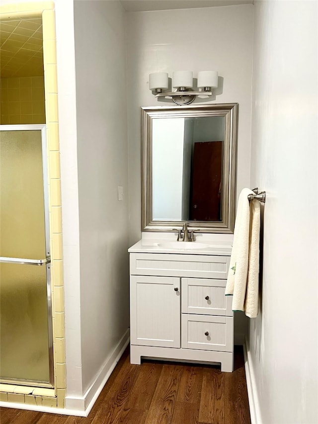 bathroom featuring wood-type flooring, a shower with door, and vanity