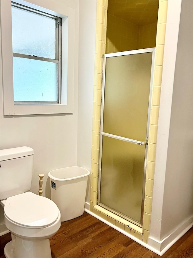 bathroom featuring hardwood / wood-style flooring, toilet, and a shower with door