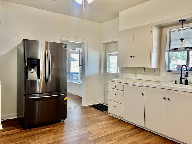 kitchen with pendant lighting, tasteful backsplash, sink, white cabinets, and stainless steel fridge