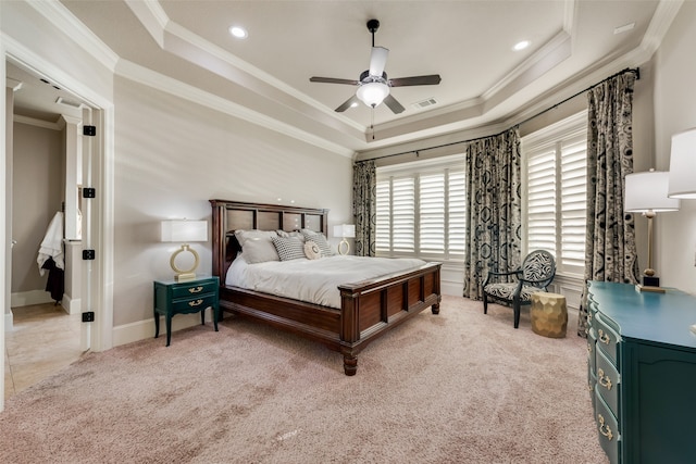 carpeted bedroom with crown molding, a tray ceiling, and ceiling fan