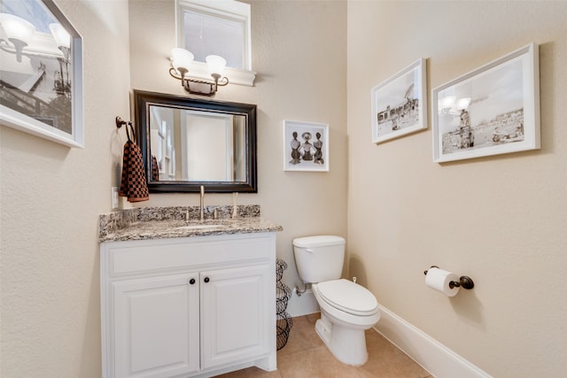 bathroom with toilet, vanity, and tile patterned flooring