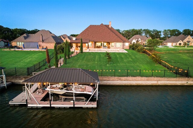 view of dock with a patio, a water view, and a lawn