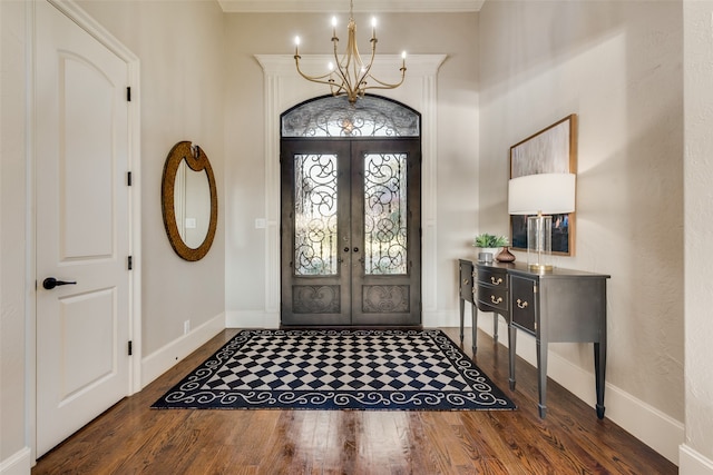 foyer with french doors, crown molding, a chandelier, and dark hardwood / wood-style flooring