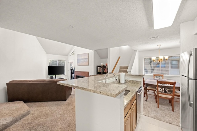 kitchen with sink, hanging light fixtures, stainless steel appliances, light stone countertops, and a chandelier