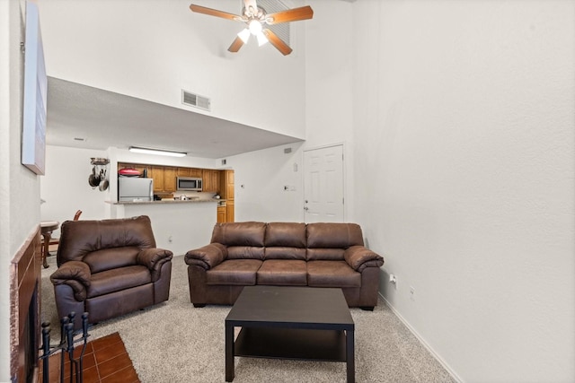 carpeted living room featuring a towering ceiling and ceiling fan