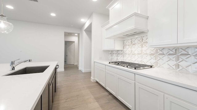 kitchen featuring white cabinetry, sink, pendant lighting, and stainless steel gas cooktop