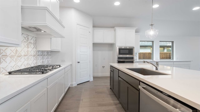 kitchen featuring white cabinetry, sink, stainless steel appliances, wood-type flooring, and decorative light fixtures