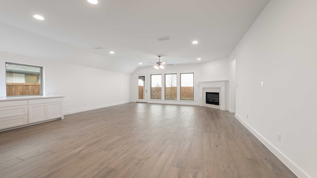 unfurnished living room with ceiling fan, light wood-type flooring, and vaulted ceiling