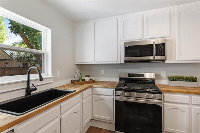 kitchen featuring butcher block counters, sink, white cabinets, and stainless steel appliances