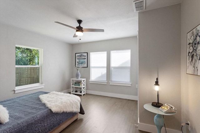 bedroom featuring multiple windows, ceiling fan, and hardwood / wood-style floors