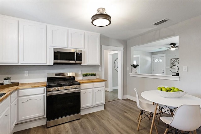 kitchen featuring white cabinets, light hardwood / wood-style flooring, ceiling fan, appliances with stainless steel finishes, and butcher block counters