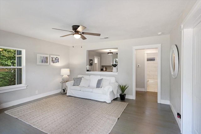 living room featuring ceiling fan and dark wood-type flooring