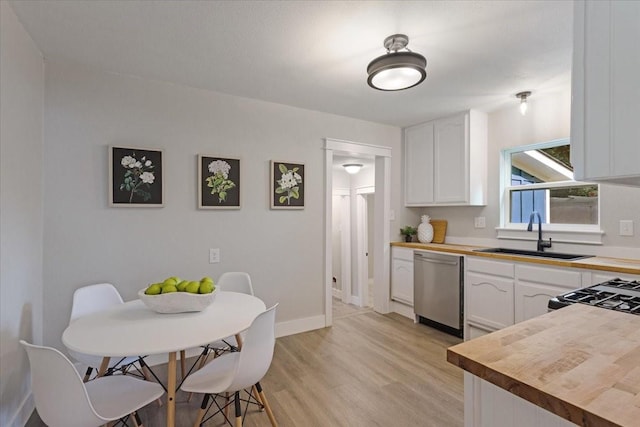 kitchen with sink, dishwasher, white cabinets, and wood counters