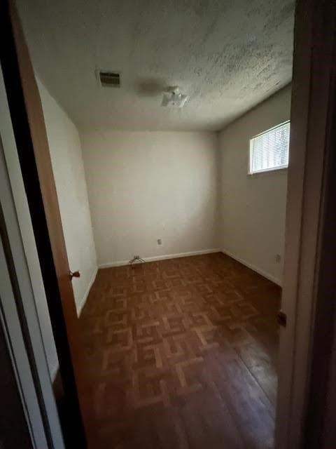 unfurnished room with a textured ceiling and parquet flooring