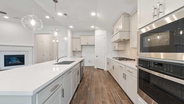 kitchen featuring appliances with stainless steel finishes, sink, dark hardwood / wood-style floors, hanging light fixtures, and a large island