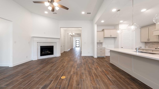 kitchen featuring decorative backsplash, ceiling fan, dark wood-type flooring, sink, and hanging light fixtures