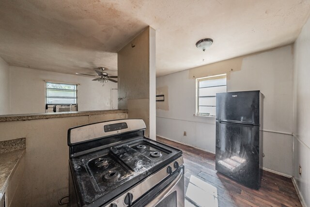 kitchen featuring ceiling fan, black refrigerator, dark hardwood / wood-style flooring, and stainless steel range oven