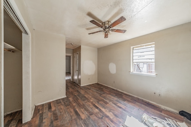 empty room with a textured ceiling, dark wood-type flooring, and ceiling fan