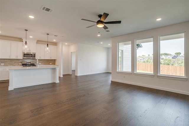 kitchen featuring white cabinetry, appliances with stainless steel finishes, a kitchen island with sink, and decorative light fixtures