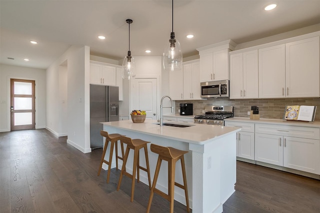 kitchen with white cabinetry, sink, stainless steel appliances, and a center island with sink