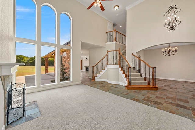 unfurnished living room featuring ceiling fan, a healthy amount of sunlight, a towering ceiling, and crown molding