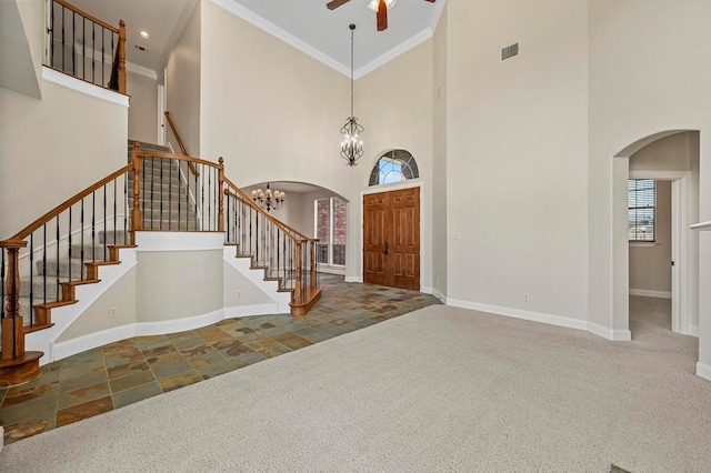 entryway with carpet, crown molding, a towering ceiling, and ceiling fan with notable chandelier