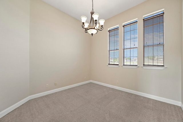 carpeted spare room featuring a notable chandelier