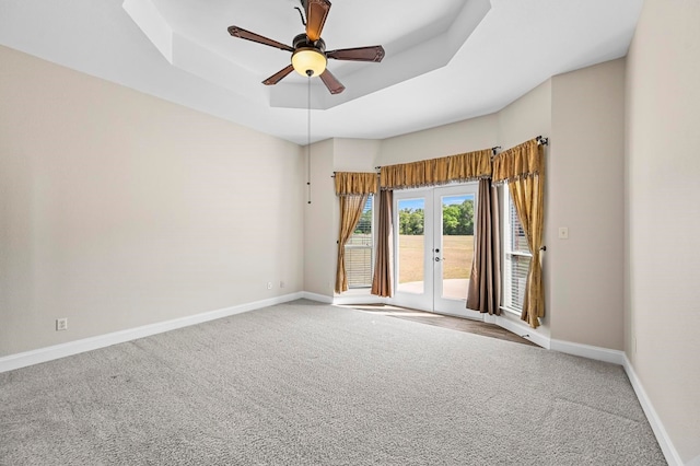 spare room with a raised ceiling, ceiling fan, french doors, and carpet flooring