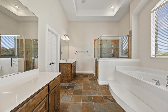 bathroom featuring vanity, independent shower and bath, and a tray ceiling