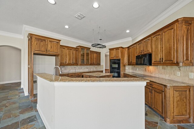 kitchen featuring backsplash, light stone counters, crown molding, black appliances, and an island with sink