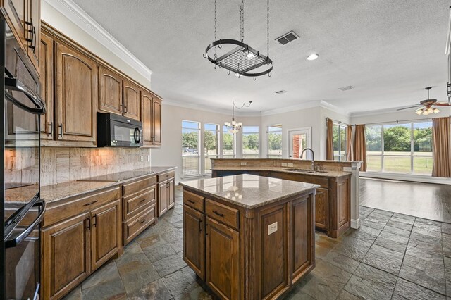 kitchen with tasteful backsplash, sink, black appliances, pendant lighting, and a kitchen island