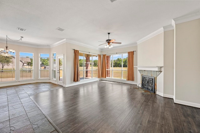 unfurnished living room featuring a tile fireplace, dark wood-type flooring, a textured ceiling, ceiling fan with notable chandelier, and ornamental molding