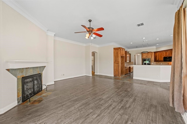 unfurnished living room with ceiling fan, a fireplace, ornamental molding, and dark wood-type flooring