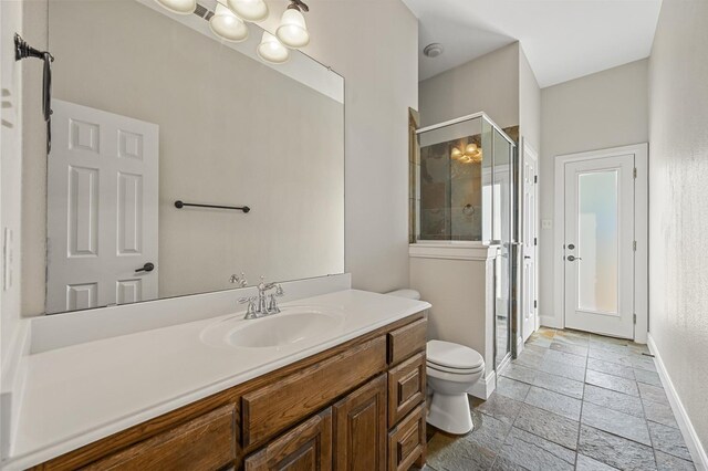 bathroom featuring vanity, toilet, and a shower with shower door