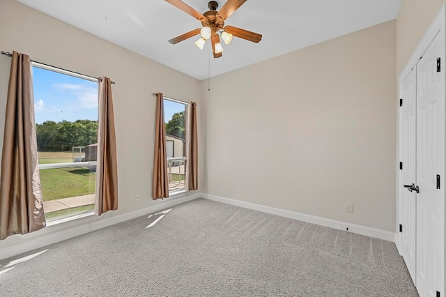 carpeted spare room featuring ceiling fan