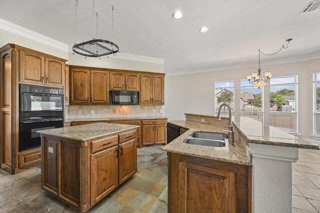 kitchen featuring a kitchen island with sink, an inviting chandelier, black appliances, sink, and decorative light fixtures