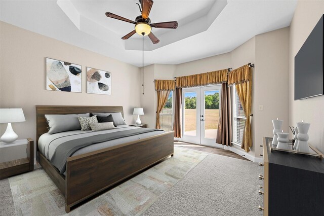 bedroom with ceiling fan, a raised ceiling, access to outside, and french doors